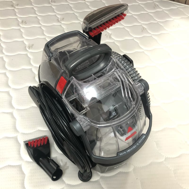 Bissell SpotClean Pro portable carpet cleaner in grey and blue with its hose, cleaning tool and two tanks