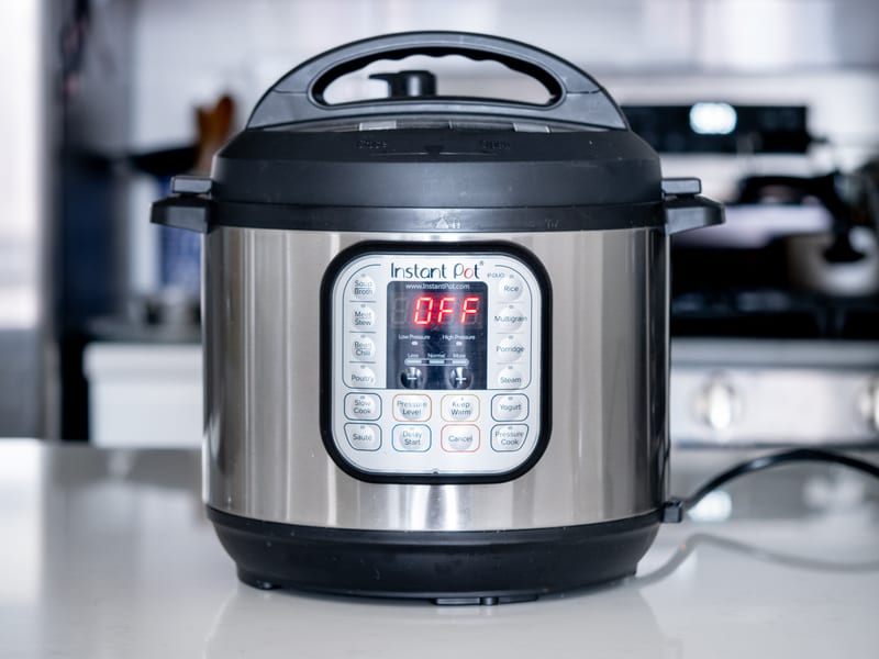 Instant Pot Duo electric pressure cooker in stainless steel and black on a kitchen counter, its IP-DUO control panel lit and reading OFF