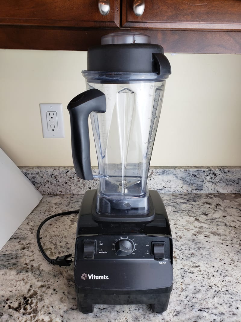 Vitamix 5200 blender in black on a kitchen counter, the tall clear container fitted and the variable speed dial and toggle switches visible on the base